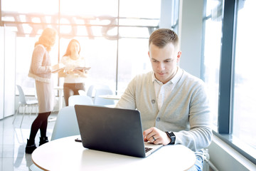 Successful young businessman typing on laptop at workplace