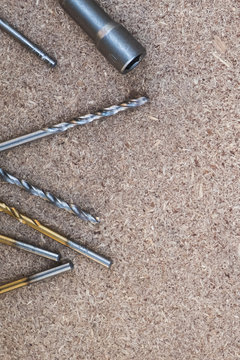 metallic screws and drills on the flake boards. Background with copy space. Concept of the DIY tools sale, apartments redecorating, reconstruction, renovation, DIY shops, home improvement.
