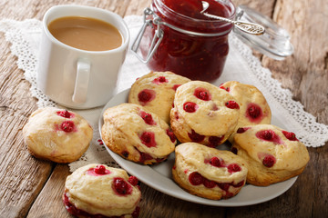 English buns sconces with red currants are served with English tea and jam close-up. horizontal