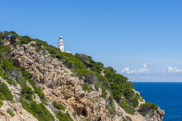 Fototapeta na wymiar Mallorca, High green plant covered cliffs with lighthouse of capdepera