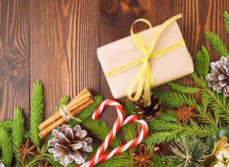 Christmas and Happy New Year background. Gift Christmas box of Kraft paper, fir branches, cones, cinnamon, wooden table.