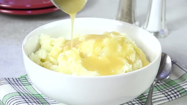 Spooning turkey gravy onto mashed potatoes