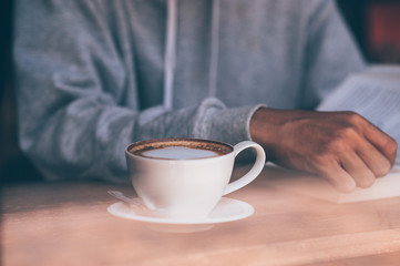 The young man sat on the couch and read a book while sipping a hot coffee. In the morning every morning.