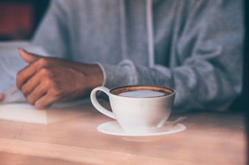 The young man sat on the couch and read a book while sipping a hot coffee. In the morning every morning.
