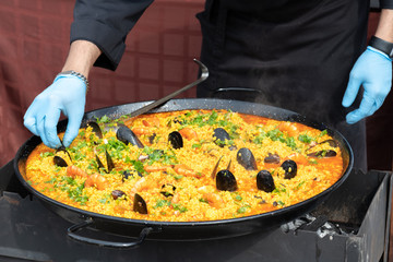 Chef hands preparing cuban seafood in big wok on food festival outdoors