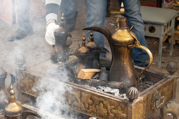 Man hands preparing arabic coffee in the national pintcher on open fire