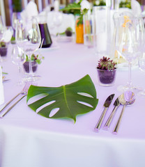 A table set up for a weeding with fresh green leaves used as a decoration