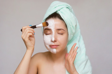 Young woman applying a face cream with brush. Face skin care concept.