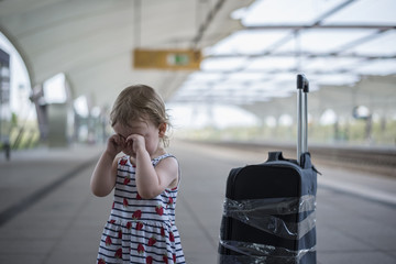  little sweet girl with a large travel suitcase on a deserted railway perone cries and a third eye.