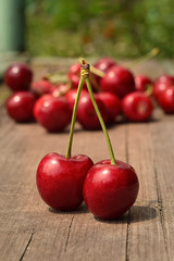 two red, ripe cherries on a wooden board
