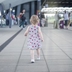 little girl the child briskly walks along the crowded perron to the excavator, the rear view.