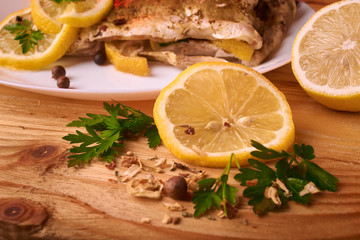 Appetizing baked fish, covered with juicy lemons, garlic and salt on side, above view