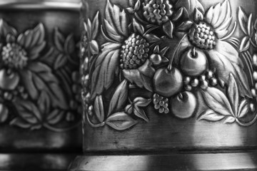 Fototapeta na wymiar Details of an old metal cup holders, decorated with a bas-relief depicting leaves, cherries and raspberries