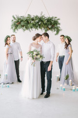 gorgeous bride with peony bouquet and stylish groom posing with bridesmaids and groomsmen on wedding day. luxury wedding couple having fun with friends