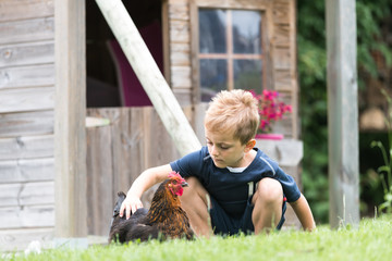 Un enfant avec ne poule dans un jardin