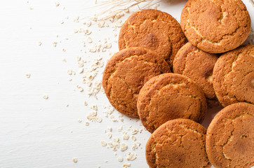 A bunch of oatmeal cookies with oat flakes on a white wooden background. Useful sweets.