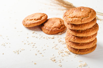 A stack of oatmeal cookies with oat flakes on a white wooden table