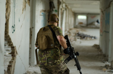 Soldier walking inside building hold down rifle