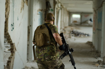 Fototapeta premium Soldier walking inside building hold down rifle