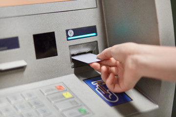 Someone takes off money from outdoor bank terminal, inserts plastic credit card in atm machine,...