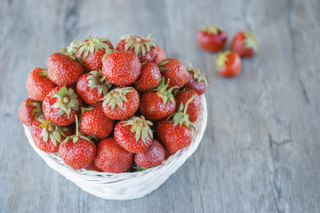 Whole red strawberry in white basket  on  gray background.