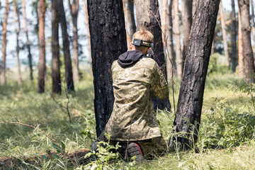 Young boys in camouflage with a gun, plays laser tag in the forest. the guy is aiming. Lasertag...