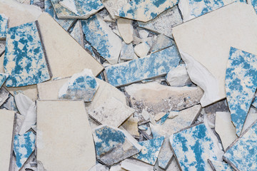 Broken tiles from demolition of an old flooring. Texture of worn retro floor pieces. Ceramic shards close-up as background. Idea of renovation and modernization of tiling and housing.