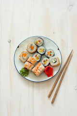 Sushi set and chopstiks on white wooden background