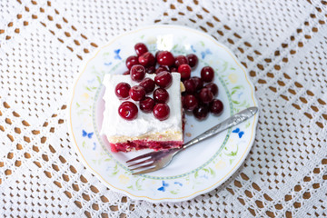 a delicious piece of cake with cherries and cream served on a plate