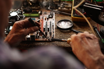 Man using soldering iron to repair circuit board