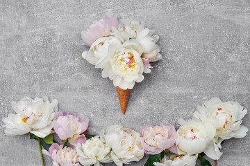 Obraz na płótnie Canvas Waffle ice cream cone with white peony flowers on gray background. Copy space, top view.