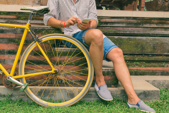 Man using cellphone while sitting on old bicycle.