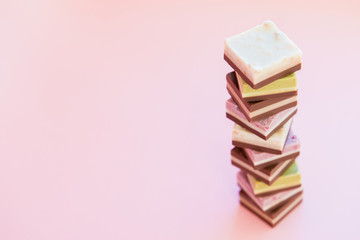 Tower made of small pieces of sweet cake on pink background