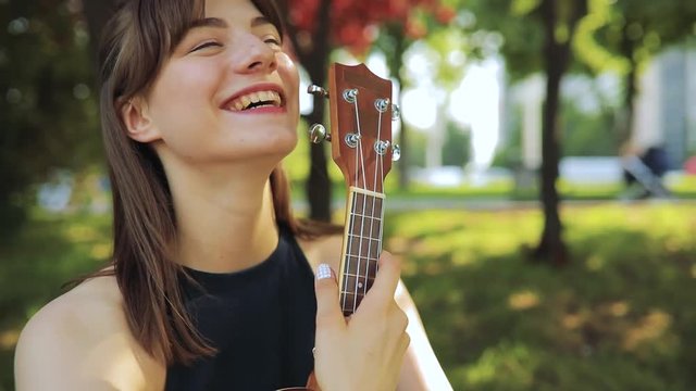 Young happy woman holding ukulele, little guitar