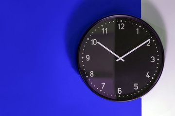 Black clock on a blue and white wall