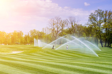 children play under the streams of watering station golf courses