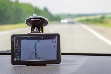 The navigator is located on the front window of the car indicating the way to the driver during the journey