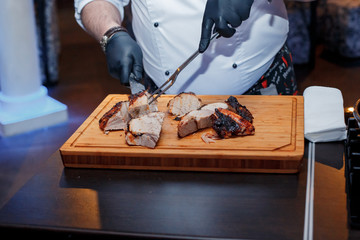 The cook cooks meat on the board, fried meat on the fire