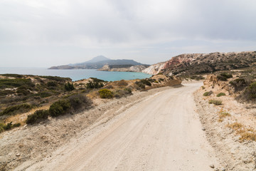 Fototapeta na wymiar Coastal dirt road along Aegean sea on Milos island, Greece