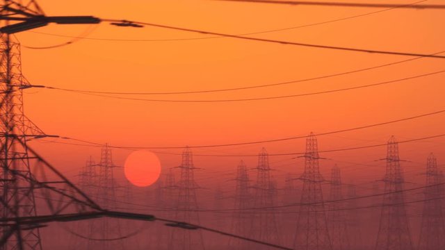 Loopable shot of high voltage electricity pylons during sunset. Bright red sky,
