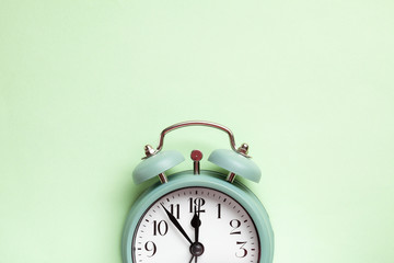 Retro style alarm clock over the pastel mint green background