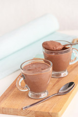 Healthy delicious chocolate yoghurt pudding serving two cups wooden cutting boarding. Selective focus.