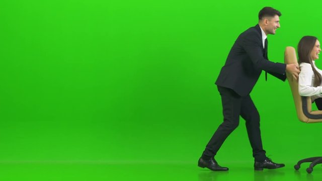 The business couple playing on the office chair on the green background