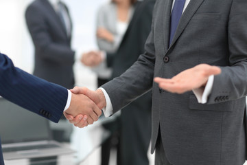 Business partners handshaking over business objects on workplace