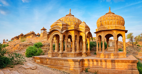Fototapeta The royal cenotaphs of historic rulers, also known as Jaisalmer Chhatris, at Bada Bagh in Jaisalmer, Rajasthan, India. Cenotaphs made of yellow sandstone at sunset obraz
