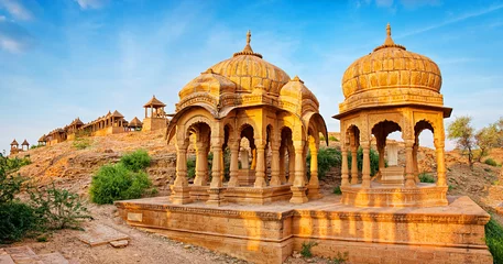 Fotobehang De koninklijke cenotaven van historische heersers, ook bekend als Jaisalmer Chhatris, in Bada Bagh in Jaisalmer, Rajasthan, India. Cenotaven gemaakt van gele zandsteen bij zonsondergang © olenatur