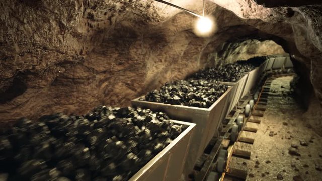 Top of a coal mine wagons slowly moving through narrow underground tunnel.
