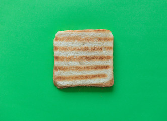 Slice of toast bread on green background, top view