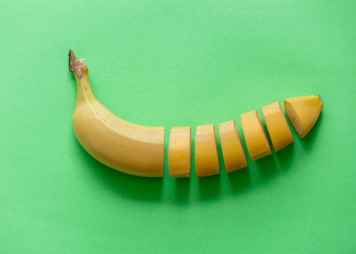 Yellow cut banana isolated on green background. Natural light