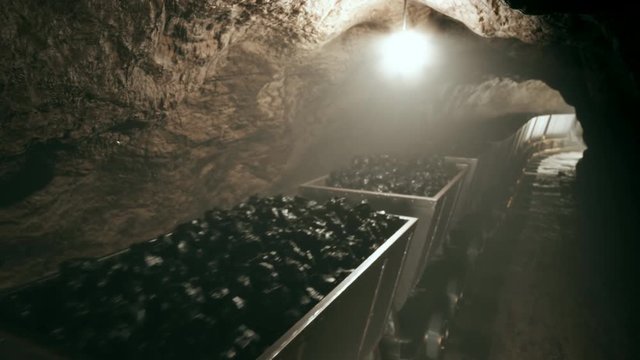 Full of coal mine wagons slowly moving through narrow underground tunnel.